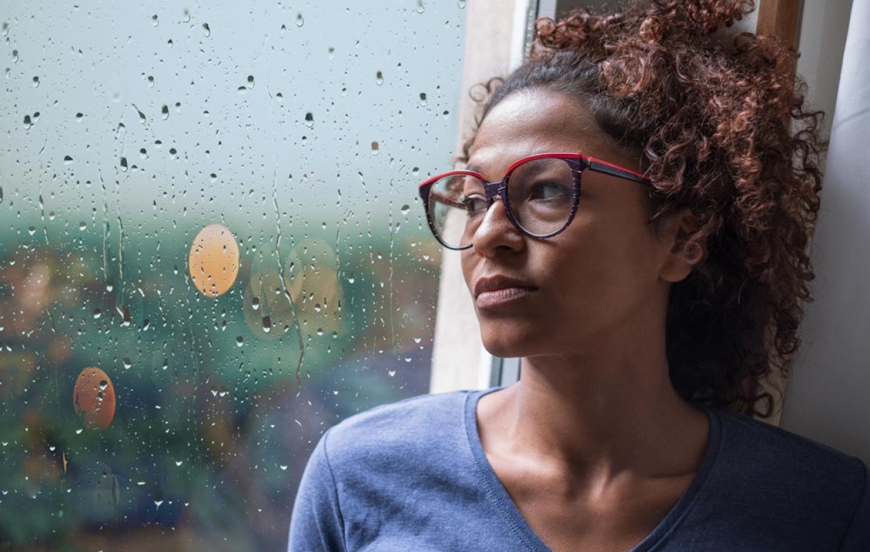 Woman looking to the rain through a window