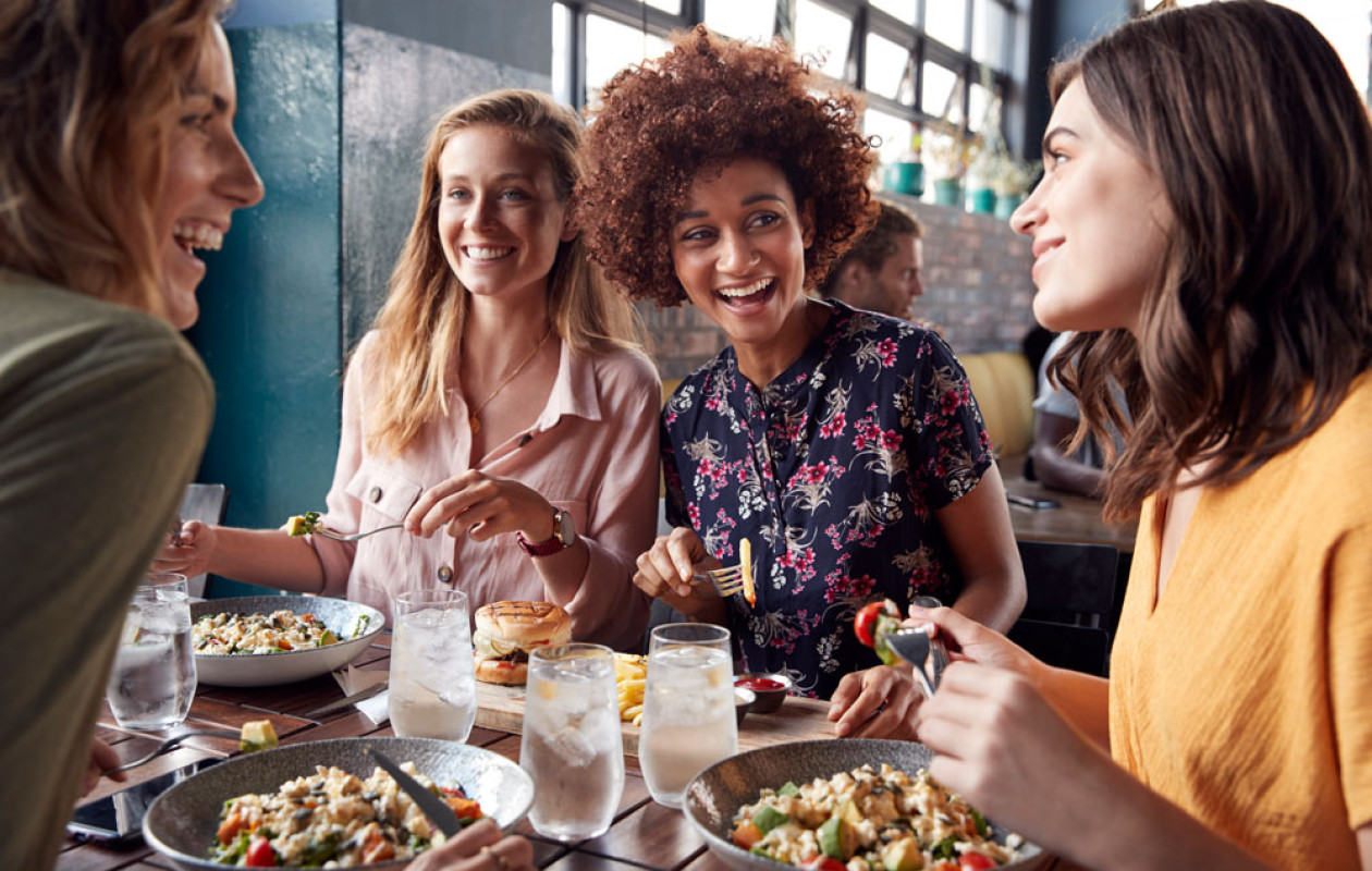 Four smiling women sitting at a table with dishes