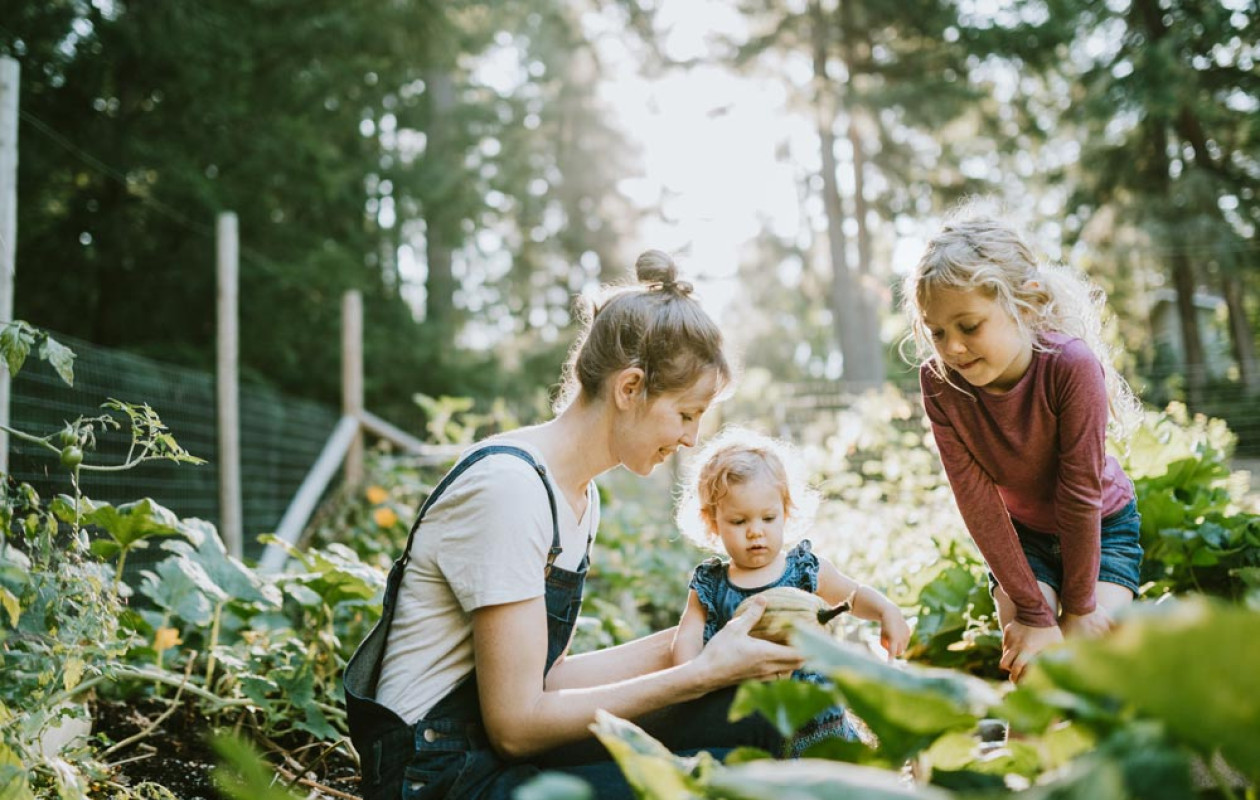 Woman with two girls looking at a vegetable in a garden