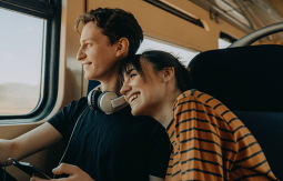 Smiling couple sitting in a train and looking outside
